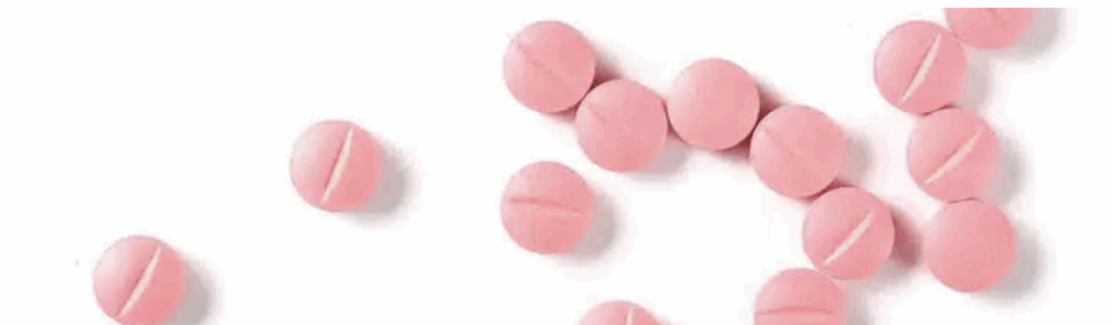 Pink Tranxene tablets scattered on a white surface, used to treat anxiety and insomnia.